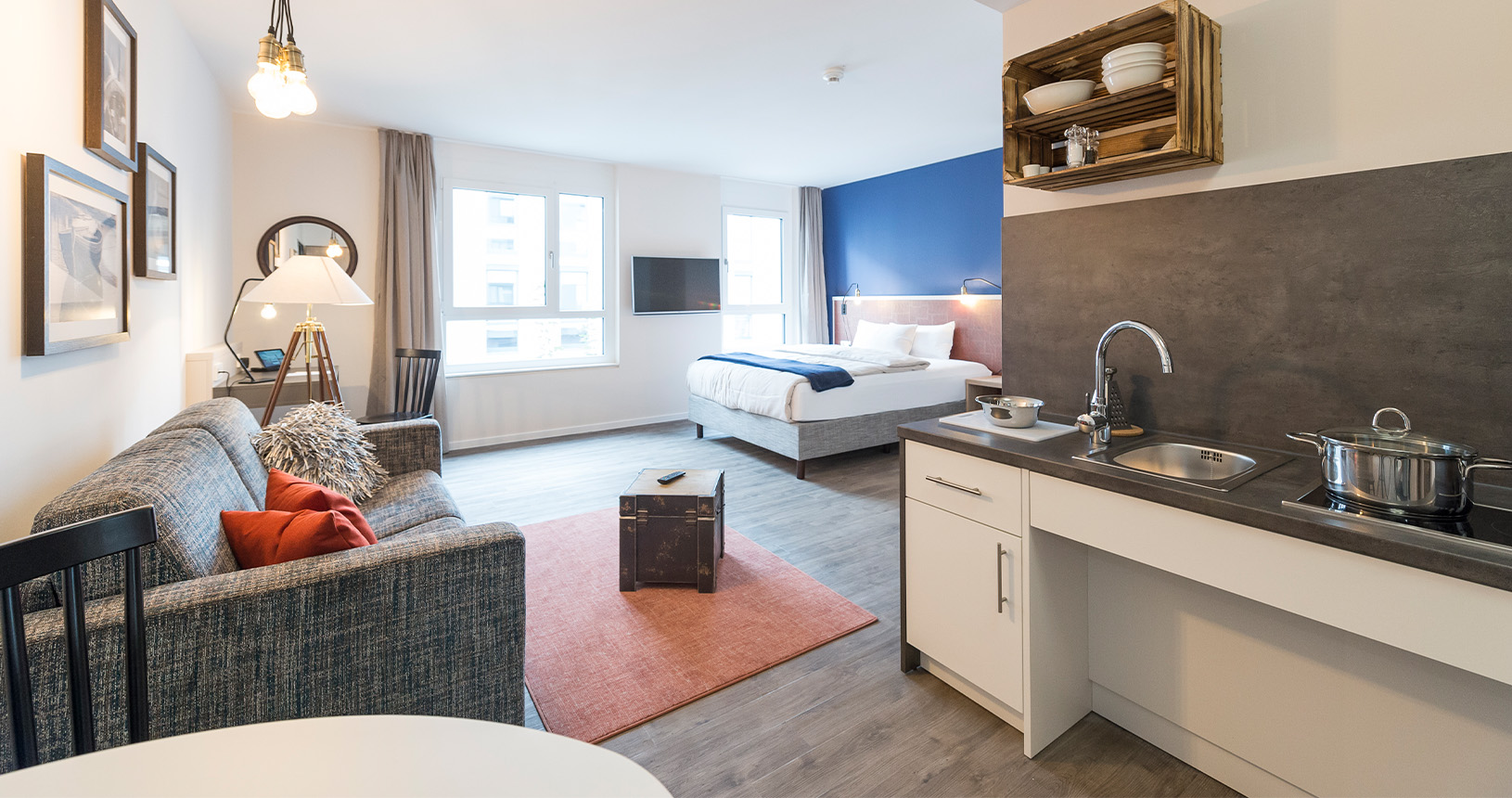 Hotelzimmer mit kleiner Kochzeile, Schreibtisch und Bettkopfteil