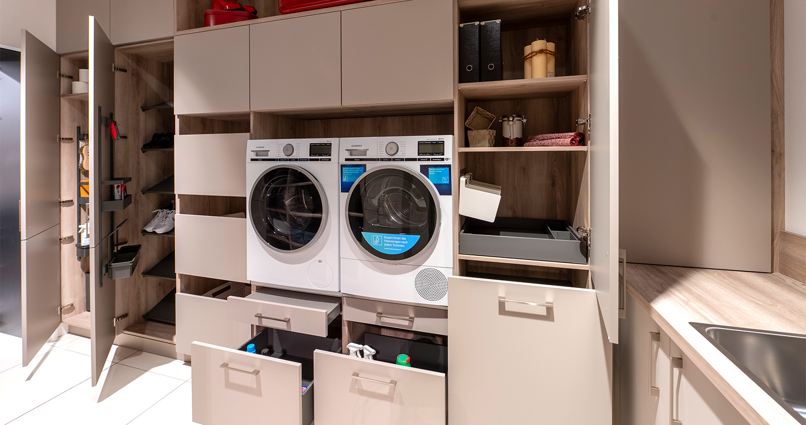 Hauswirtschaftsraum mit eingebauter Waschmaschine und Wäschetrockner in Hochschränken
